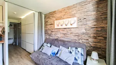 a living room with a brick wall with a couch at Résidence Sagittaire - Studio entièrement rénové avec cabine · Centre station · Balcon MAE-7390 in Flaine