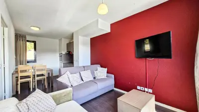 a living room with a couch and a tv on a red wall at Résidence Les Terrasses De Veret - Appartement confortable · Au pied des pistes · Piscine · Spa · Parking inclus MAE-7391 in Flaine