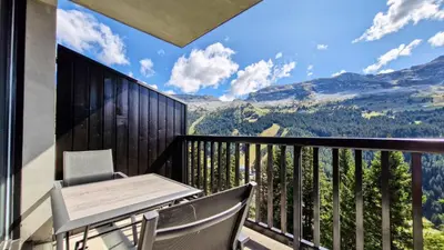 a balcony with a table and chairs and mountains at Résidence Les Pleiades - Appartement lumineux · Centre station · Balcon MAE-7393 in Flaine