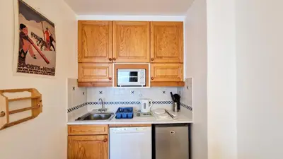 a small kitchen with wooden cabinets and a sink at Résidence Vega - Studio lumineux · Proche des pistes et des commerces · Balcon MAE-7400 in Flaine