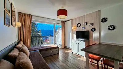 a living room with a couch and a table and a balcony at Résidence Les Pleiades - Appartement confortable · Centre station · Parking couvert · Balcon MAE-7401 in Flaine