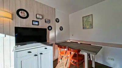 a dining room with a table and a television at Résidence Les Pleiades - Appartement confortable · Centre station · Parking couvert · Balcon MAE-7401 in Flaine