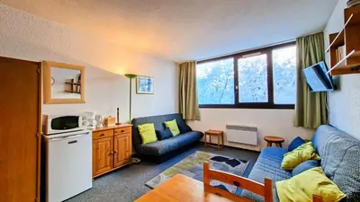 a living room with a blue couch and a kitchen at Résidence Andromede - Studio spacieux · Proche des pistes MAE-7407 in Flaine