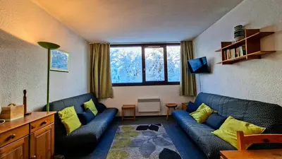 a living room with a blue couch and yellow pillows at Résidence Andromede - Studio spacieux · Proche des pistes MAE-7407 in Flaine