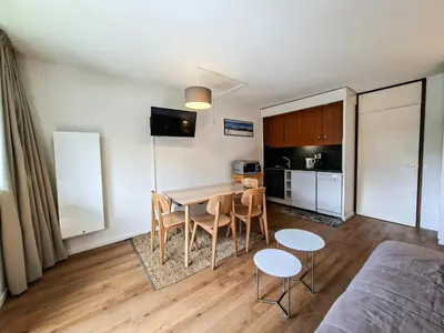 a living room with a table and chairs and a kitchen at Résidence Gemeaux - Studio confortable · Centre station · Balcon MAE-7410 in Flaine