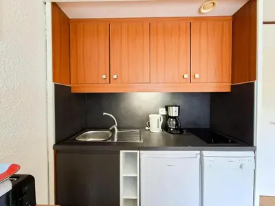 a small kitchen with wooden cabinets and a sink at Résidence Gemeaux - Studio confortable · Centre station · Balcon MAE-7410 in Flaine