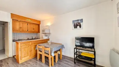 a small kitchen with a table and a television at Résidence Andromede - Studio rénové · Proche des pistes · Balcon · Casier à ski MAE-7411 in Flaine
