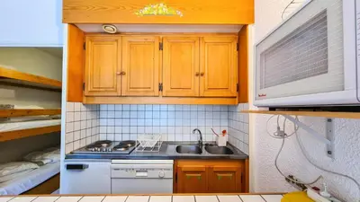 a small kitchen with wooden cabinets and a sink at Résidence Andromede - Studio rénové · Proche des pistes · Balcon · Casier à ski MAE-7411 in Flaine