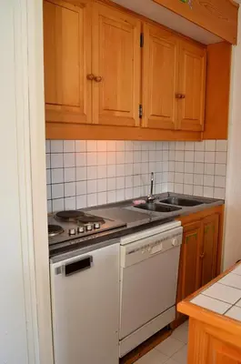 a kitchen with wooden cabinets and a white stove top oven at Résidence Andromede - Studio rénové · Proche des pistes · Balcon · Casier à ski MAE-7411 in Flaine