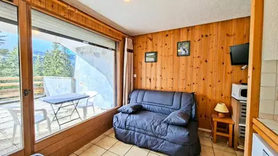 a living room with a couch and a balcony at Résidence Arche - Studio confortable · Centre station · Terrasse MAE-7414 in Flaine