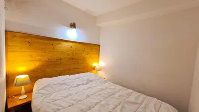 a bedroom with a white bed and a wooden wall at Résidence Arche - Studio confortable · Centre station · Terrasse MAE-7414 in Flaine