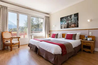 a hotel room with a large bed and a chair at Chalet Hôtel La Sapinière in Chamonix-Mont-Blanc