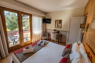 a bedroom with a large bed and a balcony at Chalet Hôtel La Sapinière in Chamonix-Mont-Blanc