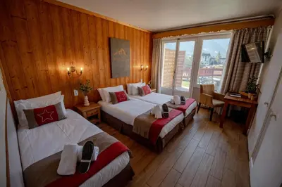 a hotel room with two beds and a window at Chalet Hôtel La Sapinière in Chamonix-Mont-Blanc