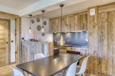 a kitchen with wooden cabinets and a table and chairs at Appartement Eskimo in Megève