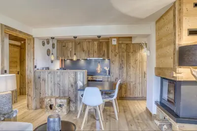 a kitchen with wooden cabinets and a table and chairs at Appartement Eskimo in Megève