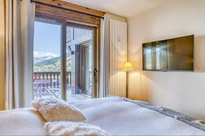 a bedroom with a bed and a large window at Appartement Eskimo in Megève