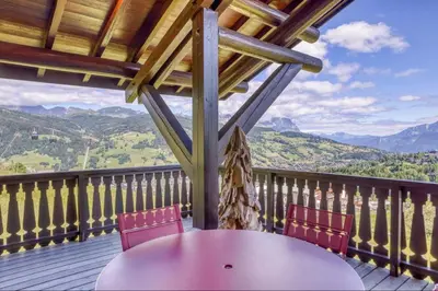 a table and chairs on a deck with a view of mountains at Appartement Eskimo in Megève
