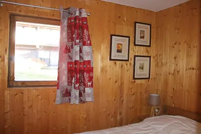 a bedroom with a wooden wall with a bed and a window at Comfortable Apartment With Terrace In Chamonix in Chamonix-Mont-Blanc