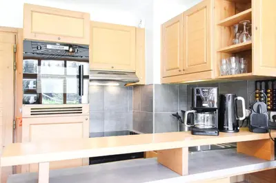 a kitchen with wooden cabinets and a counter top at 1-bed apartment in 5* Residence with mountain views, ski in, ski out in Flaine