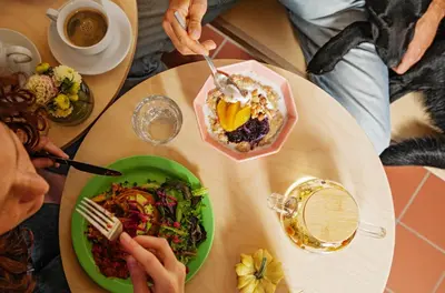 a table with a plate of food and a bowl of salad at Cosmiques Hotel - Centre Chamonix in Chamonix-Mont-Blanc
