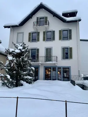 a large white house with a snow covered yard at Cosmiques Hotel - Centre Chamonix in Chamonix-Mont-Blanc