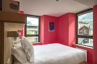 a red room with a bed and two windows at Cosmiques Hotel - Centre Chamonix in Chamonix-Mont-Blanc