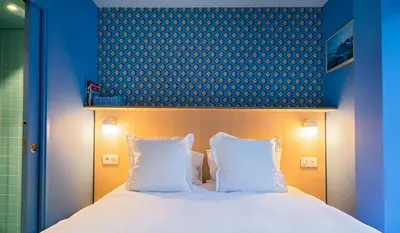 a bed with two white pillows and a blue wall at Cosmiques Hotel - Centre Chamonix in Chamonix-Mont-Blanc
