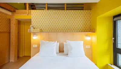a bedroom with a bed with white pillows and a yellow wall at Cosmiques Hotel - Centre Chamonix in Chamonix-Mont-Blanc