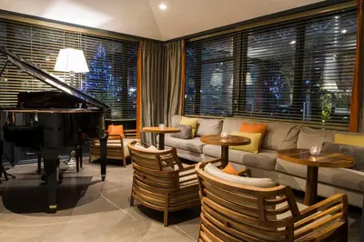 a living room with a couch and a piano at Hôtel Mont-Blanc Chamonix in Chamonix-Mont-Blanc