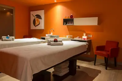 a treatment room with two beds and a red chair at Hôtel Mont-Blanc Chamonix in Chamonix-Mont-Blanc