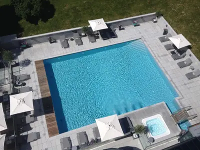 an overhead view of a swimming pool with white umbrellas at Hôtel Mont-Blanc Chamonix in Chamonix-Mont-Blanc