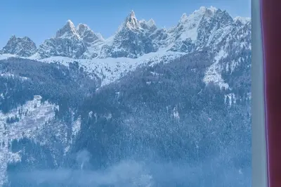 a snow covered mountain with trees and a mountain at Hôtel Mont-Blanc Chamonix in Chamonix-Mont-Blanc