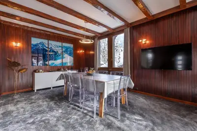 a dining room with a table and a flat screen tv at Chalet Clos 66 in Chamonix-Mont-Blanc