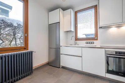 a kitchen with white cabinets and a stainless steel refrigerator at Chalet Clos 66 in Chamonix-Mont-Blanc