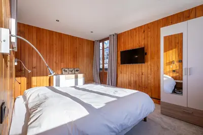 a bedroom with a white bed and wooden walls at Chalet Clos 66 in Chamonix-Mont-Blanc