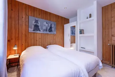 a bedroom with a white bed and wooden walls at Chalet Clos 66 in Chamonix-Mont-Blanc