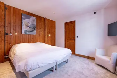 a bedroom with a white bed and a chair at Chalet Clos 66 in Chamonix-Mont-Blanc