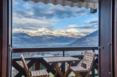 a table and chairs on a balcony with a view of mountains at Studio Cosy coin-nuit proche centre - Vue splendide in Saint-Gervais-les-Bains