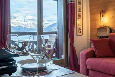a table with two wine glasses on top of a balcony at Studio Cosy coin-nuit proche centre - Vue splendide in Saint-Gervais-les-Bains
