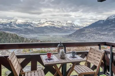 a wooden table with two chairs on a balcony with mountains at Studio Cosy coin-nuit proche centre - Vue splendide in Saint-Gervais-les-Bains