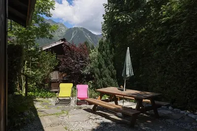 a picnic table with two chairs and an umbrella at Le Chalet du Petit Ours in Chamonix-Mont-Blanc