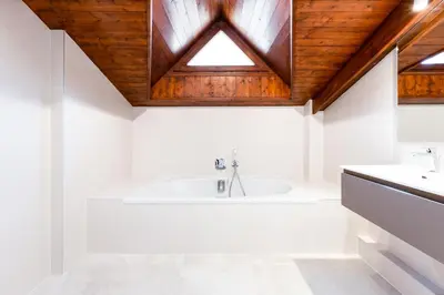 a bathroom with a bath tub and a wooden ceiling at Chalet Les Praz - 280sqm - Sauna Cinema Fitness - 5 Bedrooms in Heart of Les Praz - By Cozee Rentals in Chamonix-Mont-Blanc