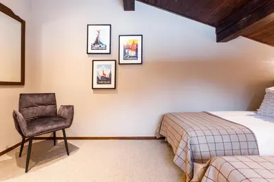 a bedroom with two beds and a chair in it at Chalet Les Praz - 280sqm - Sauna Cinema Fitness - 5 Bedrooms in Heart of Les Praz - By Cozee Rentals in Chamonix-Mont-Blanc