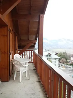a porch with two chairs and a table on a balcony at Spacious and comfortable chalet apartment. in Saint-Gervais-les-Bains