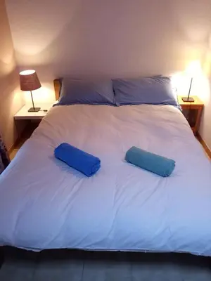 a large white bed with two blue pillows on it at Spacious and comfortable chalet apartment. in Saint-Gervais-les-Bains