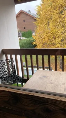 a wooden bench sitting on a porch with a table at Oree Studio Mezzanine in Megève