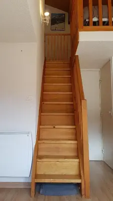 a staircase in a room with a bed at RED APPLE CARROZ Duplex de charme WIFI Parking Balcon TV Ski-Bus in Les Carroz d'Araches