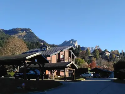 a house with a car parked in a parking lot at RED APPLE CARROZ Duplex de charme WIFI Parking Balcon TV Ski-Bus in Les Carroz d'Araches
