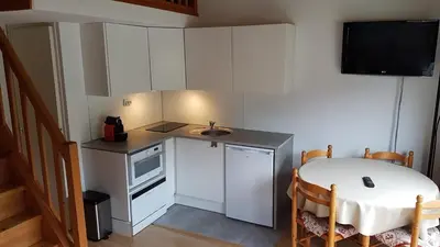 a small kitchen with a table and a sink at RED APPLE CARROZ Duplex de charme WIFI Parking Balcon TV Ski-Bus in Les Carroz d'Araches